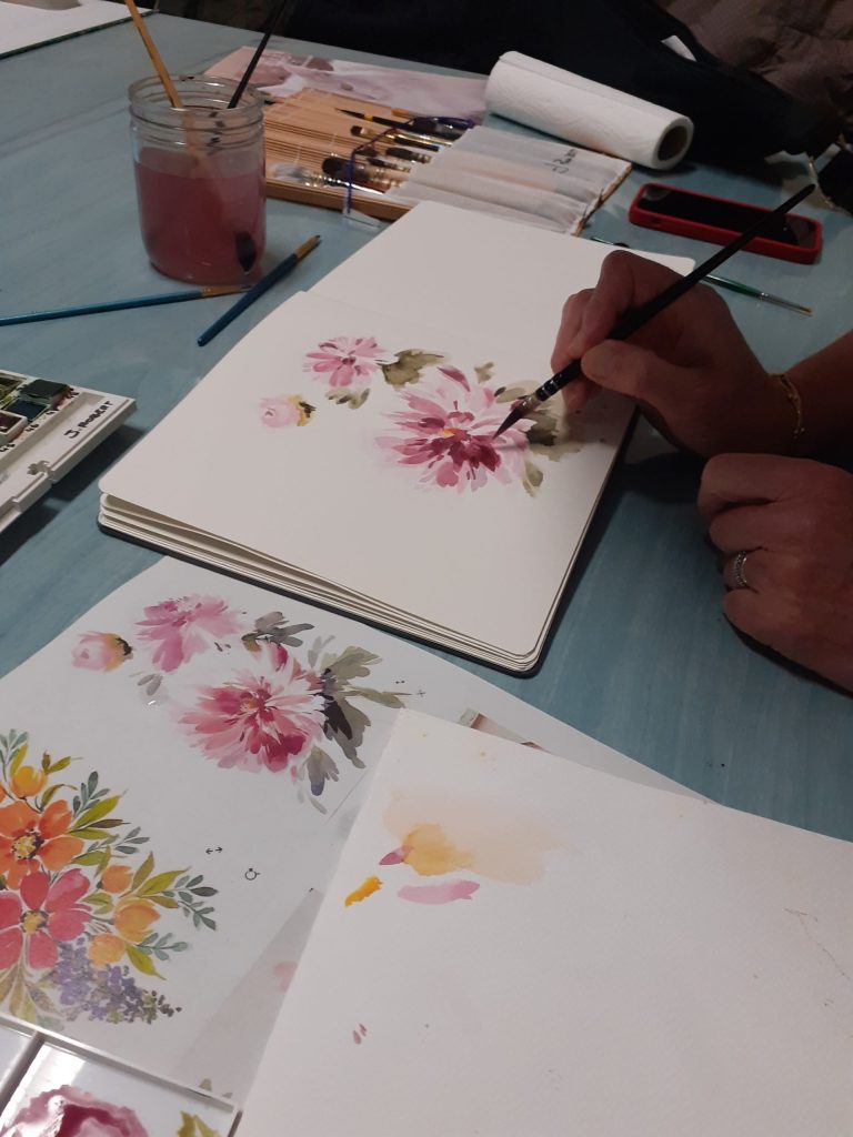 Personne entrain de peindre une fleur rose