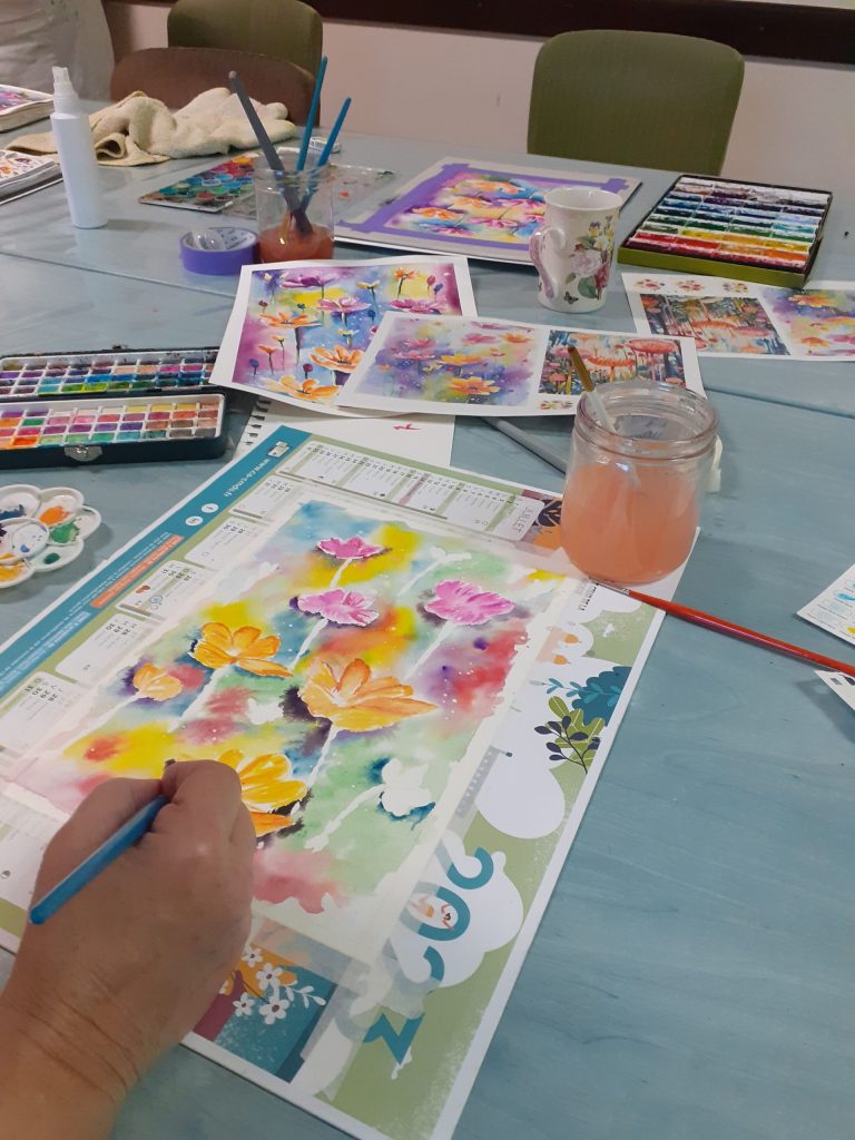 Personne entrain de peindre à l'aquarelle des fleurs de couleurs vives