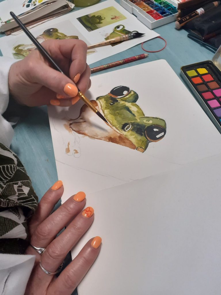 Personne entrain de peindre à l'aquarelle une tête de grenouille