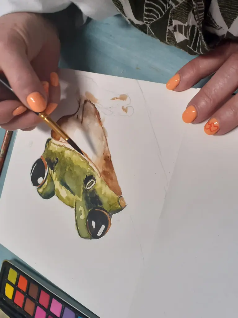 Personne entrain de peindre à l'aquarelle une tête de grenouille